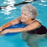 mujer-mayor-feliz-tabla-flotacion-piscina_256588-2057